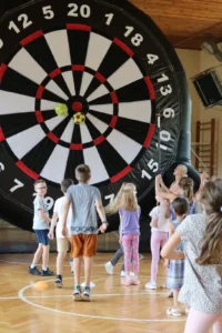 grupa bawiąca się podczas zajęć na letniej półkolonii, rzutki mega dart, ogromna dmuchana tarcza do darta