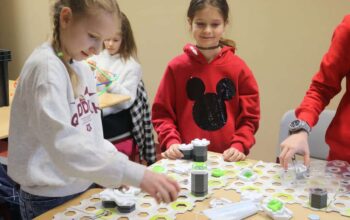 grupa dzieci układa klocki i gra w gry planszowe